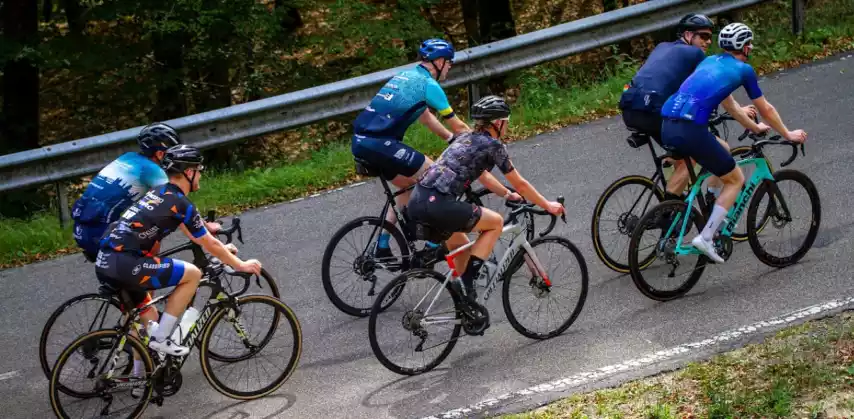 Groep wielrenners beklimt samen een asfaltweg op de racefiets.